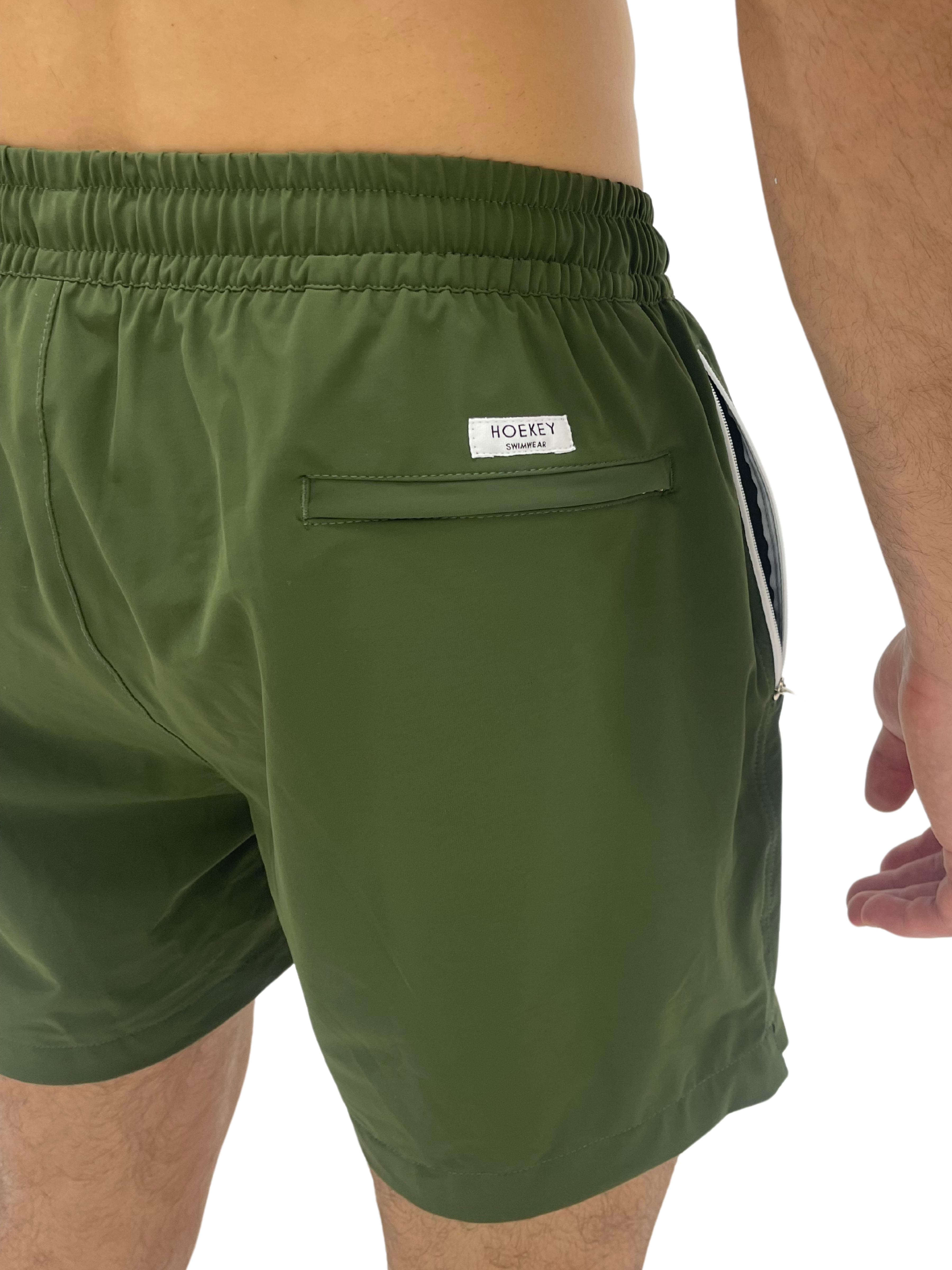 Hoekey olive green men’s swim shorts featuring quick-dry fabric, elastic waistband, back zippered pocket with logo detail, and a secure fit for versatile wear.