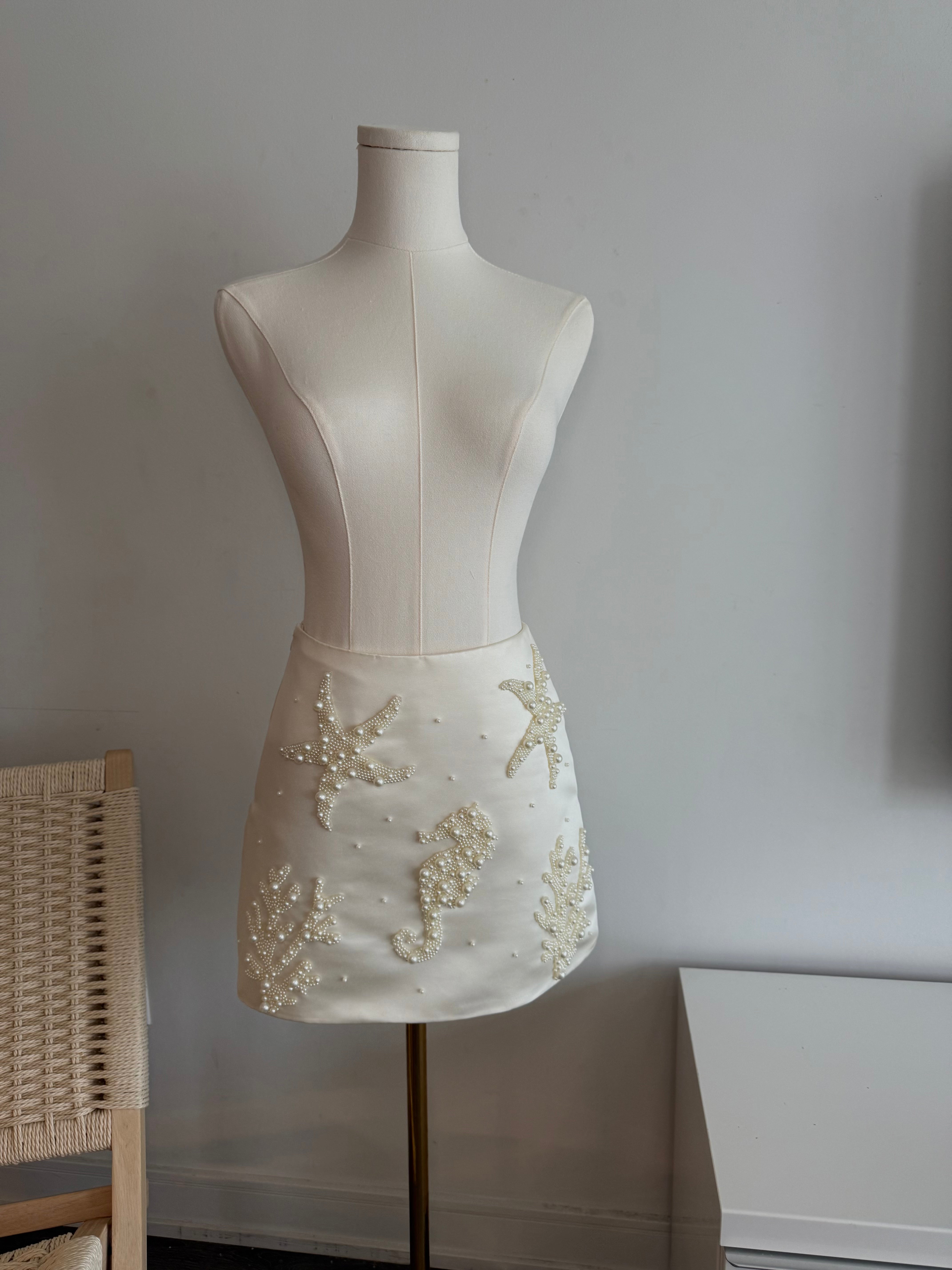 Hoekey pearl-embellished ivory mini skirt featuring beaded starfish, a seahorse, and coral motifs on smooth satin for an elegant coastal vibe.