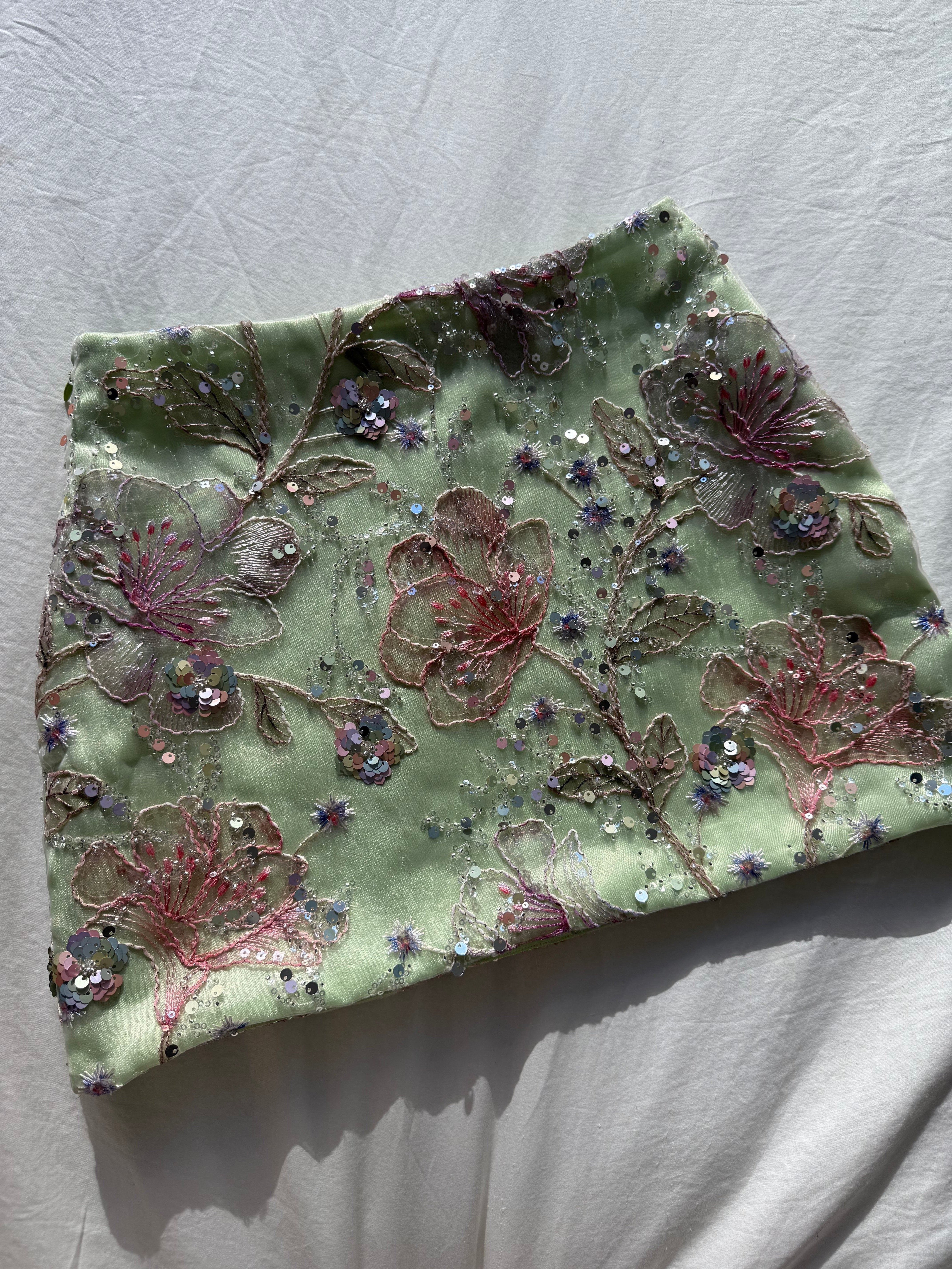 Hoekey pastel green embroidered mini skirt with pink floral appliqué, sequin embellishments, and delicate beaded detailing for a feminine and elegant look.